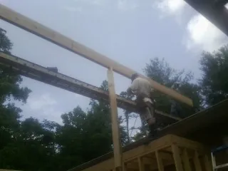 Carpenter setting a ridge beam over a new addition frame — Ice Dam Removal by Roofing Brothers in Vance