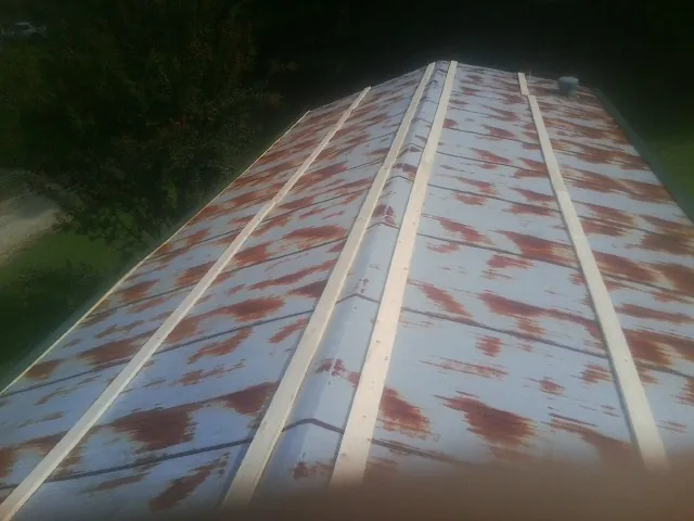 Rusted metal roof panels with new wood purlins before replacement — Storm Damage Roof Repair in Vance by Roofing Brothers