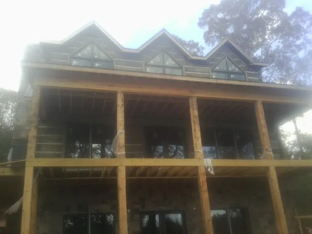 Dormers and porch framing on a large log home under construction — Roof Coating work by our crew in Vance